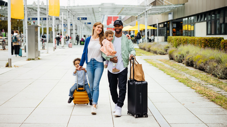 A happy family walking through an airport with luggage