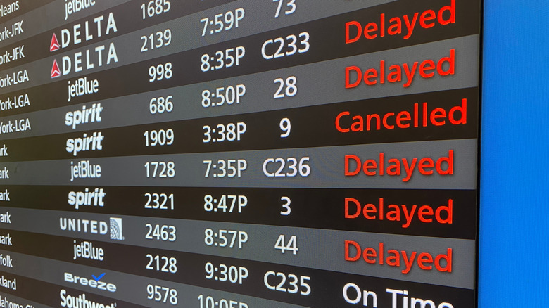 An airport board listing cancelled and delayed flights.