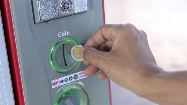 Close-up photo of hand vending a coin in the auto vending machine