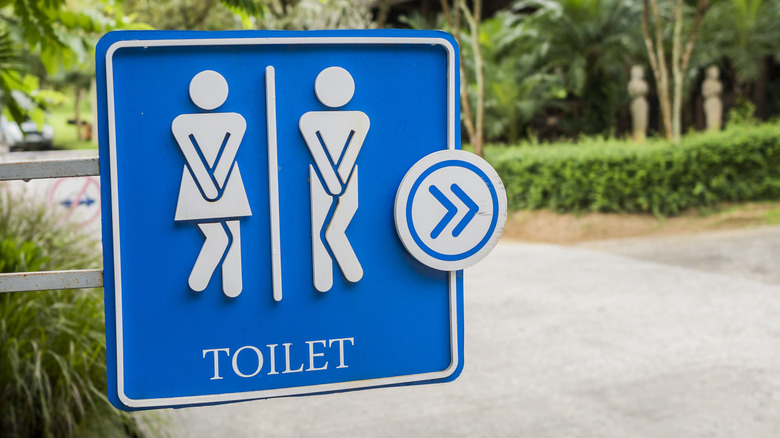 sign for a restroom with both the man and woman figure crossing their legs as if desperate to pee.