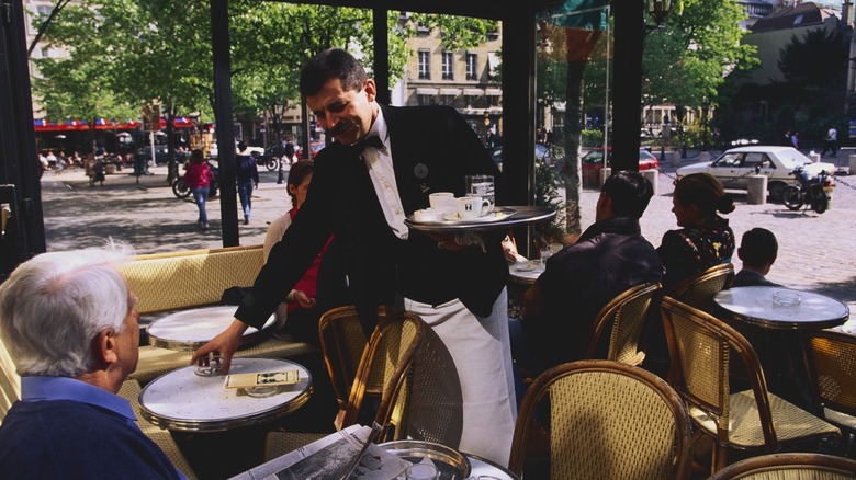 a person reading the newspaper at a cafe table