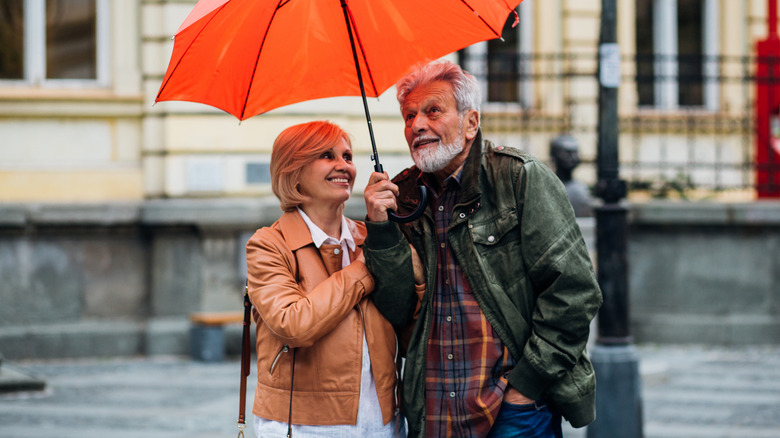 man holding umbrella for woman