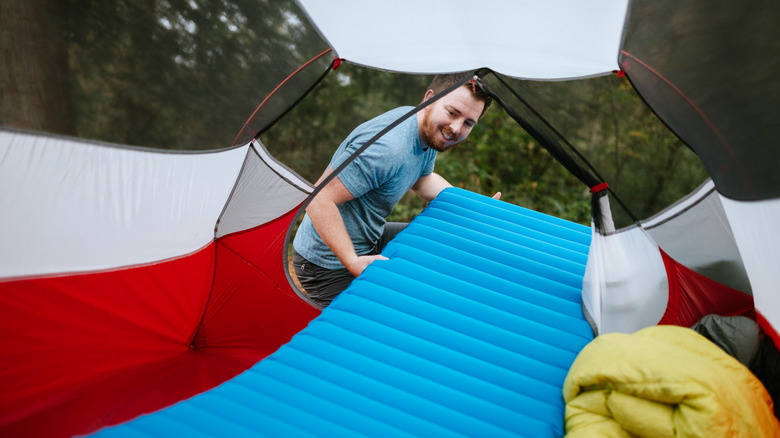 Man sets up sleep pad in tent