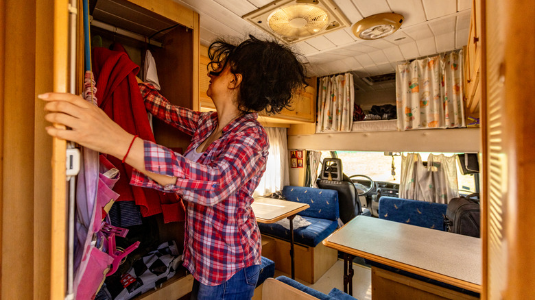 A person reaching into a full campervan closet.