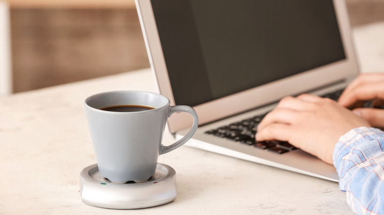 A coffee cup and laptop on a table