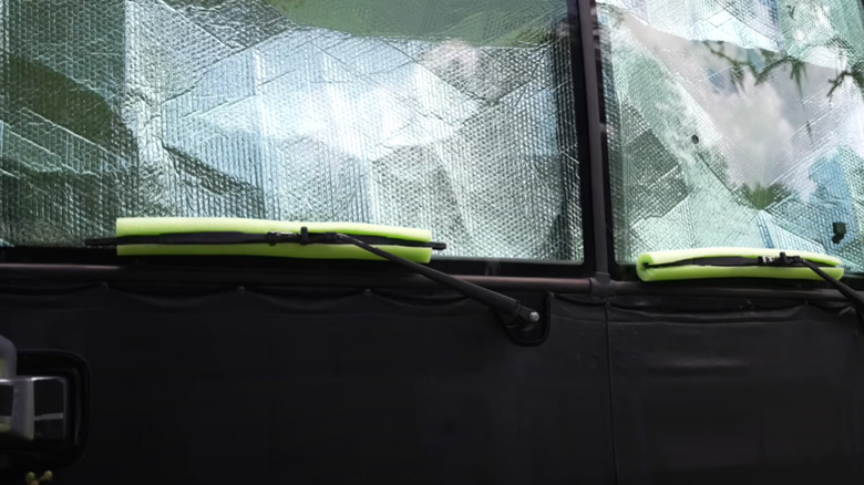 Green pool noodle resting under windshield wipers on an RV