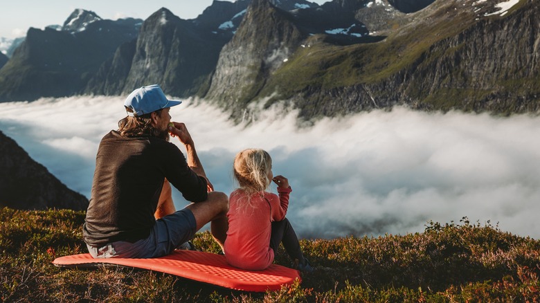 Father and daughter eating snacks overlooking mountains