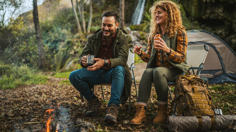 happy man and woman having fun eating while camping