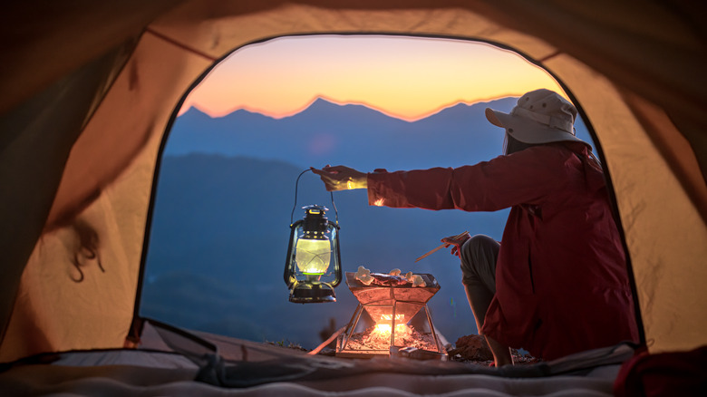 view from tent of camper grilling food over fire