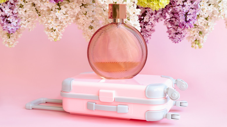 A brown perfume bottle on top of a pink suitcase