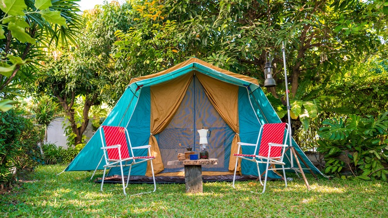 A camping site with text and two camping chairs surrounded by greenery