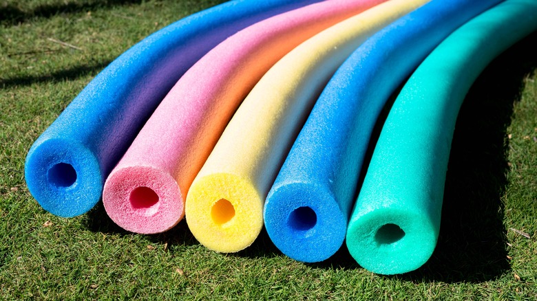 pool noodles in various colors laying on grass