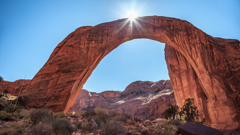 The sun flares behind the Rainbow Bridge in Utah