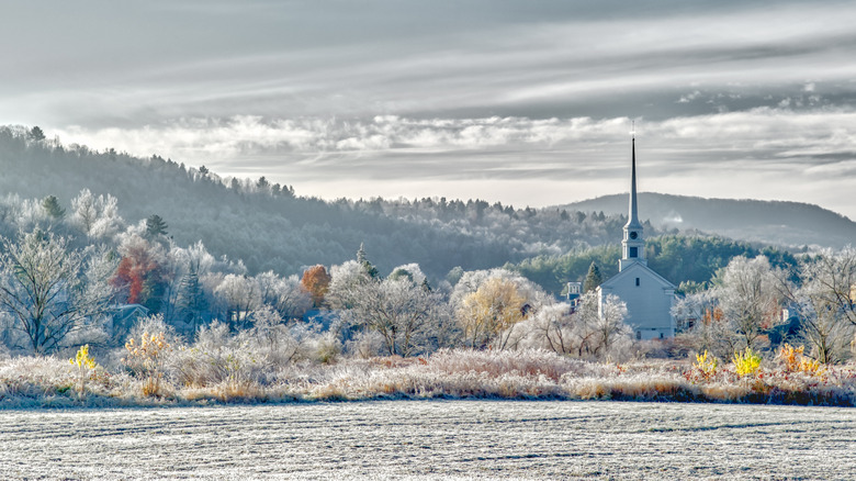 The Stowe Community Church with snow-covered mountains in the picturesque town of Stowe, Vermont.