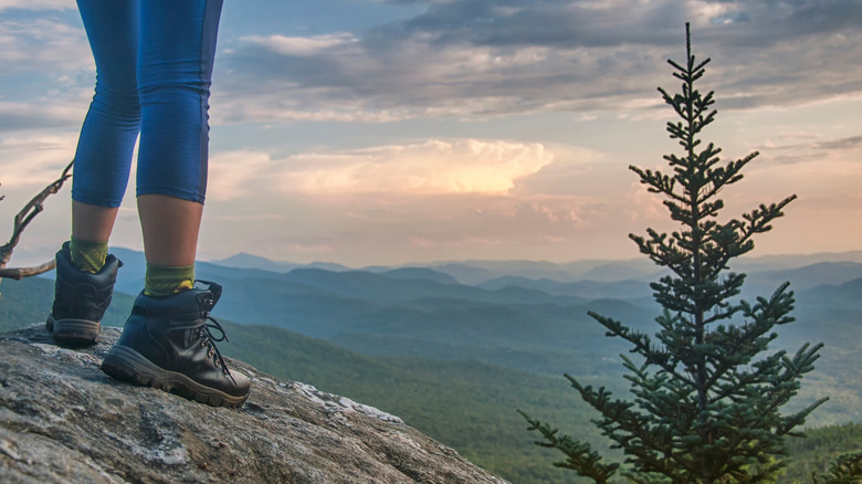 A woman stands on a rocky cliff above the Green Mountains in Vermont