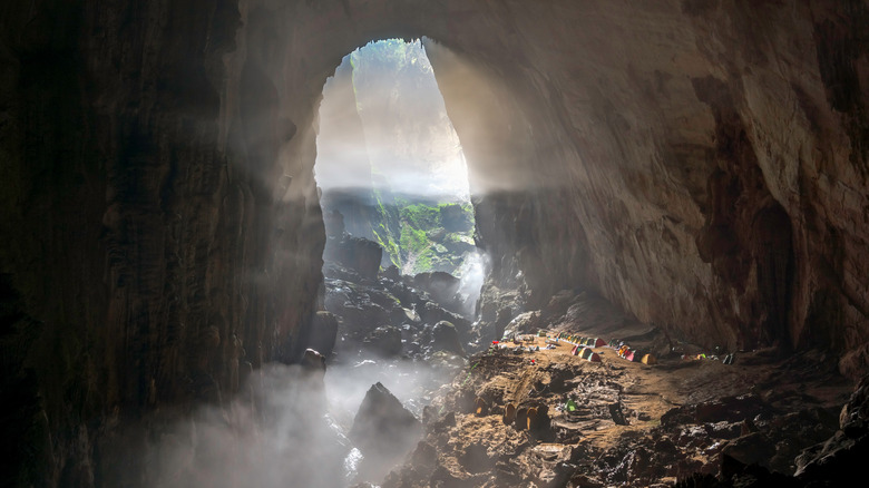 Tiny tents in front of the giant opening of Son Doong cave in Vietnam