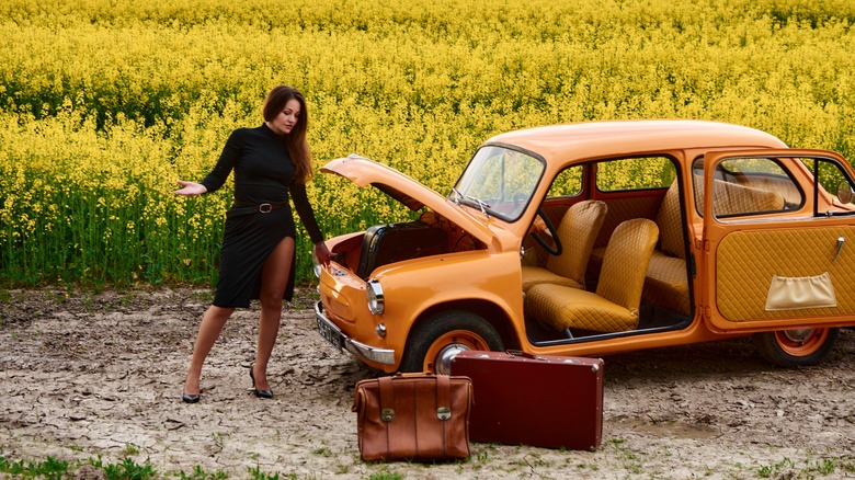 woman packs vintage car with vintage suitcase