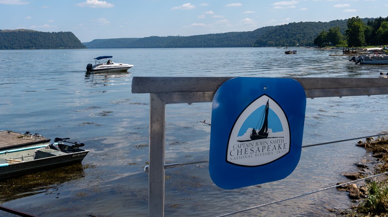 Signage for the Captain John Smith National Historic Trail  on a dock, with boats sailing in the background