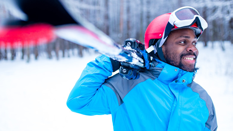 Happy man holding skies in snow