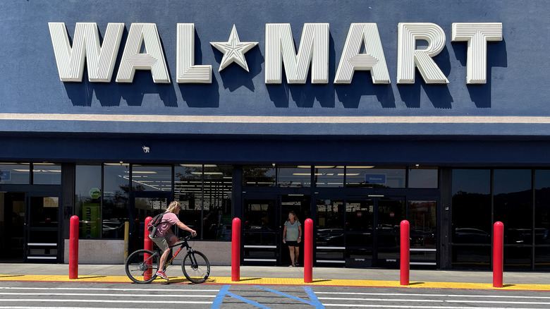 A woman rides a bicycle past the entrance of a Walmart store