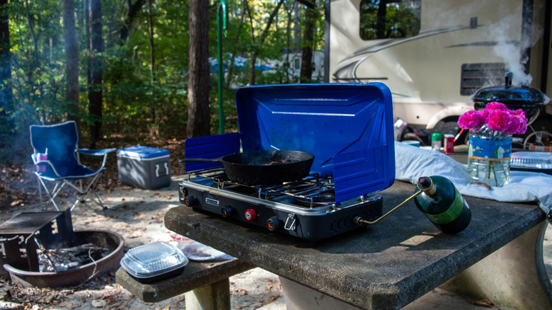 A camp stove with propane tank at a campsite.