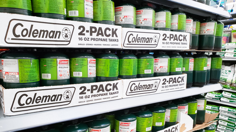 Camping propane tanks on a store shelf.
