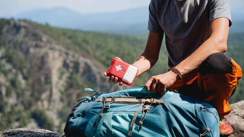 Hand holding a first aid kit against the background of mountains