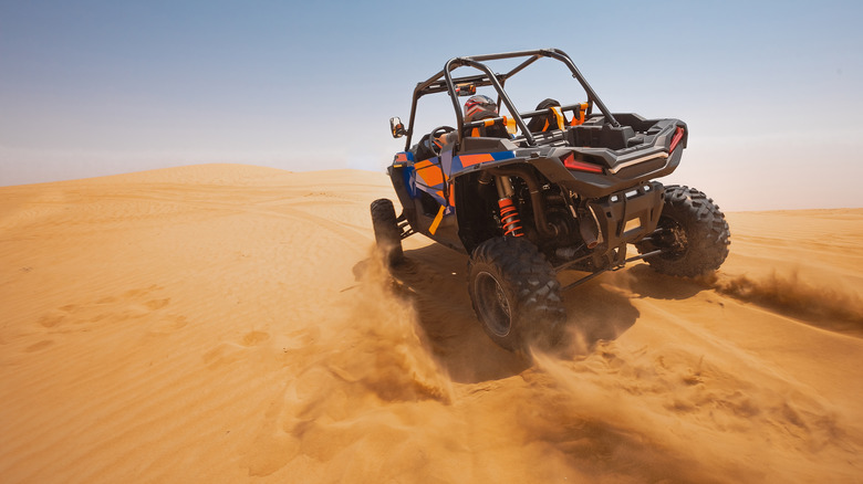 An ATV riding across sand dunes.