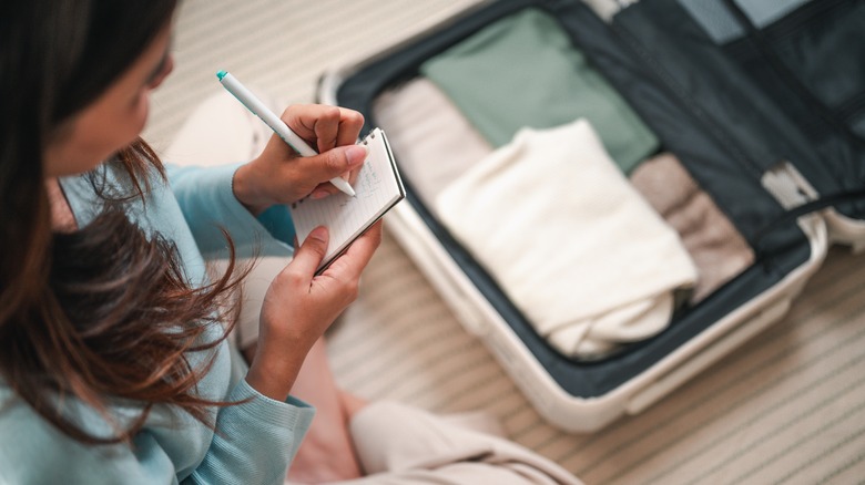 Woman making a packing list over her suitcase