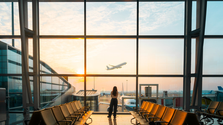 Young woman looks out the windows at an airport terminal