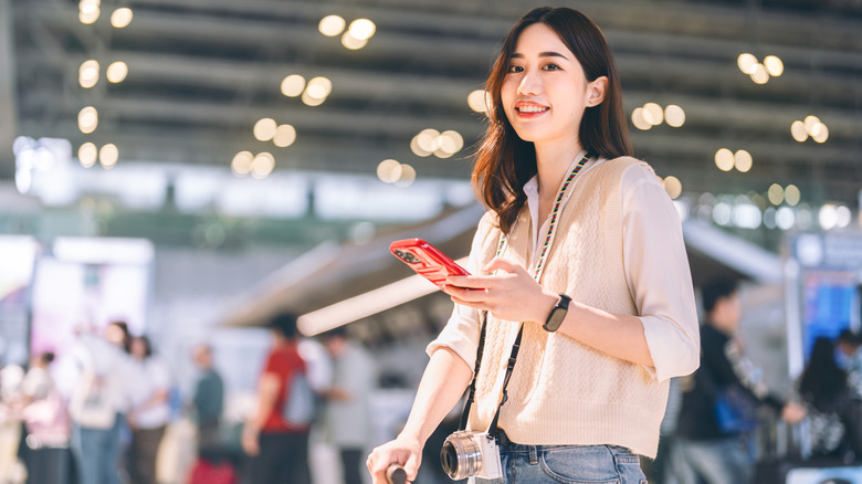 Young Asian woman in airport with phone in her hand