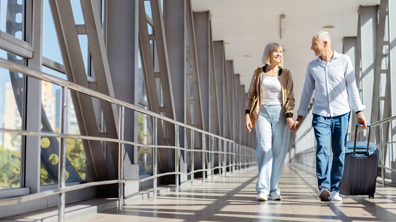 couple holding hands walking through an airport