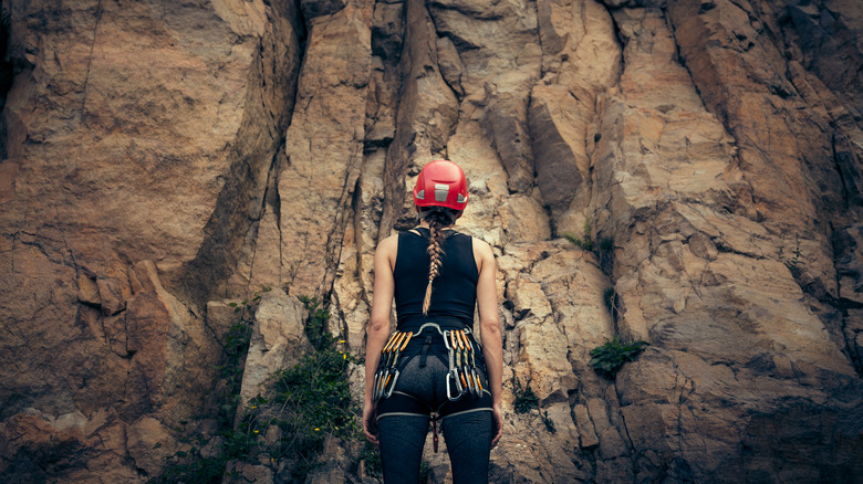 Young rock climber looking at cliff face