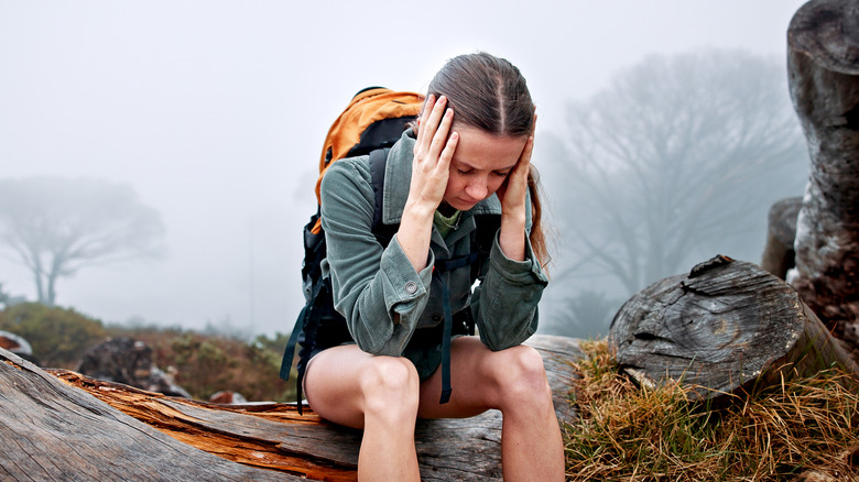 Lost hiker sitting on log in fog