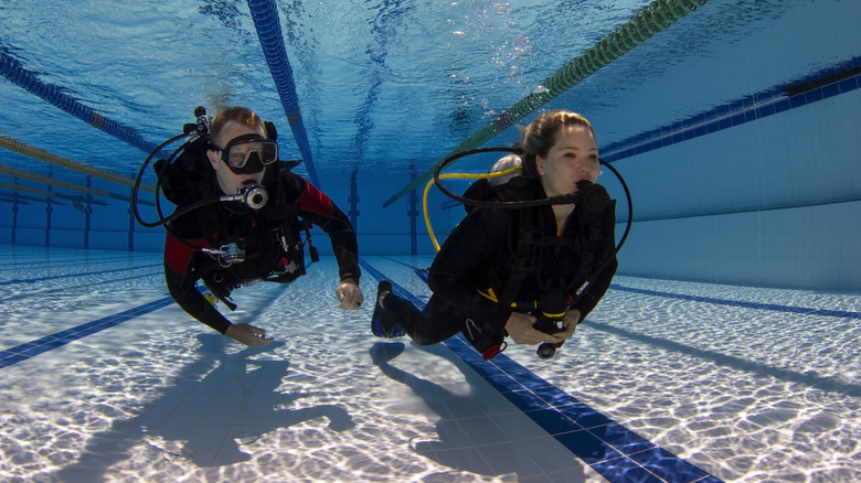 Two scuba divers train in a swimming pool