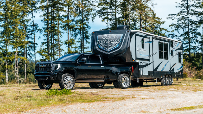 Truck with attached trailer parked outside near trees