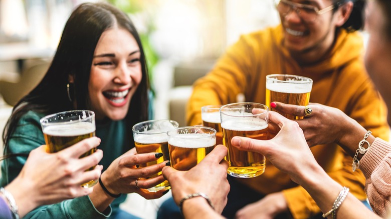 A group of young people enjoy a toast of beer glasses