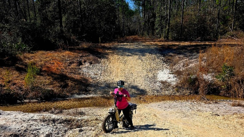a woman cycling on a sandy forest track in Shoal River Headwaters State Park