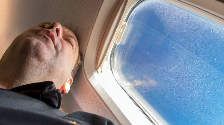 A person sitting beside airplane window