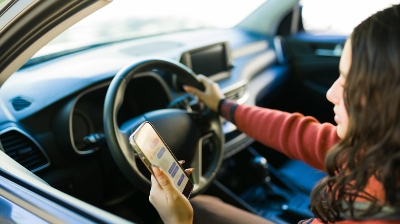A woman uses a phone while driving