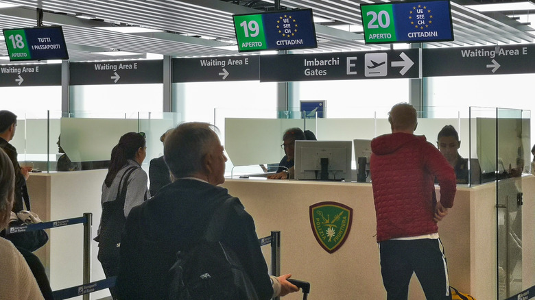 Passengers wait for border security at an Italian airport.