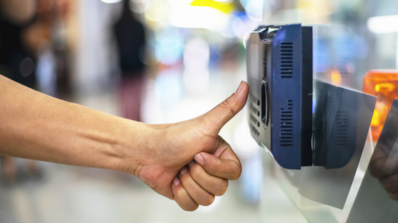 A hand holding the thumb up to a security scanner.