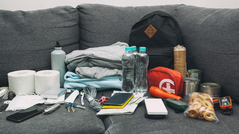 An emergency kit with toilet paper, blankets, flashlights, water, crackers, and other safety items.
