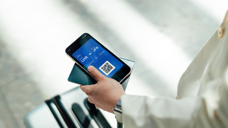 woman holds her phone passport and boarding pass in the airport