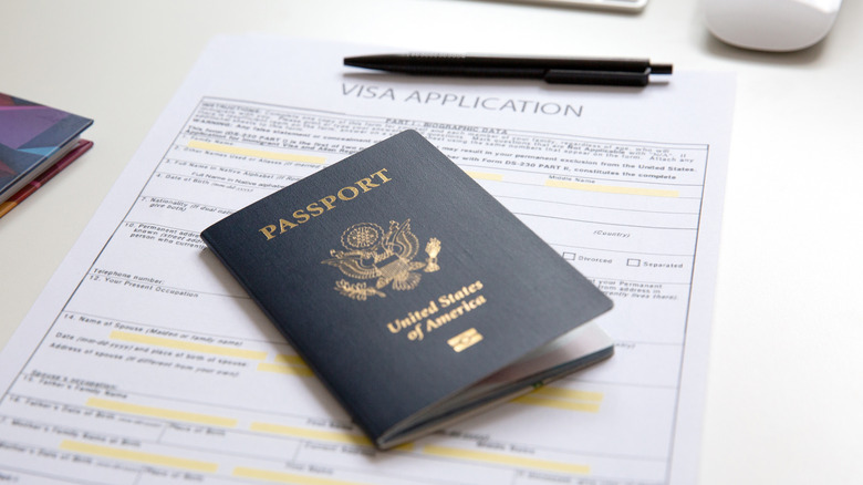 An American passport, visa application, and pen on an office table.