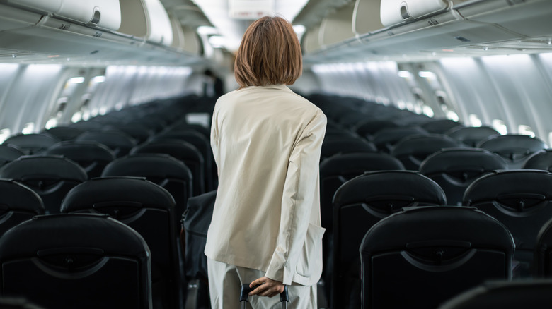 Woman walking down plane aisle