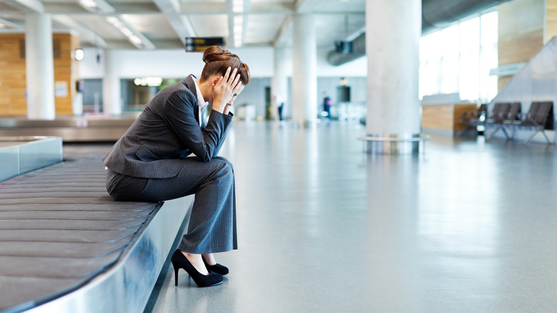 woman palming temples at airport