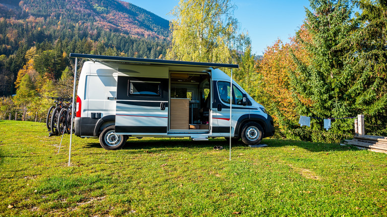 A camper van in a forest and hills.