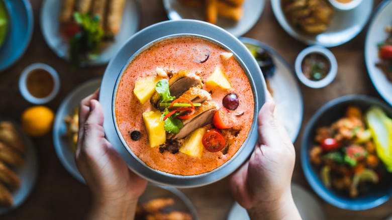 a Thai dish held above a table of other plates with food