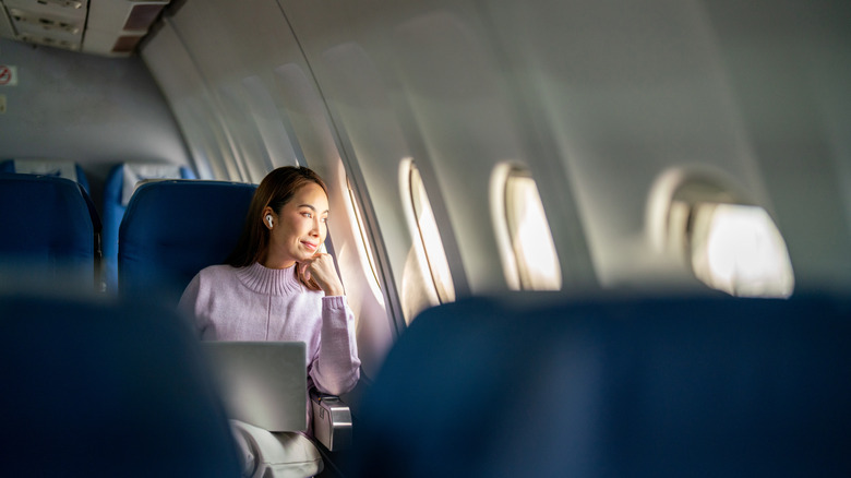 woman relaxes and enjoys outside view from an airplane window